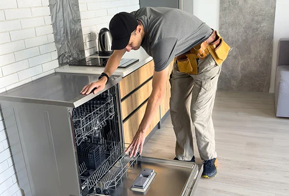 Appliance repair technician fixing a dishwasher, highlighting professional service.