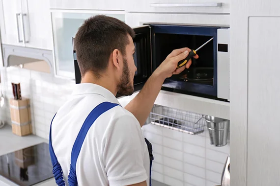 Technician working on a built-in oven, highlighting the benefits of professional oven repair services.