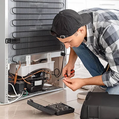 Technician working on a refrigerator, representing reliable appliance repair services.