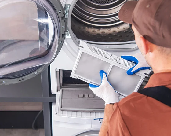 Technician cleaning a lint filter on an electric dryer, representing electric dryer repair services.