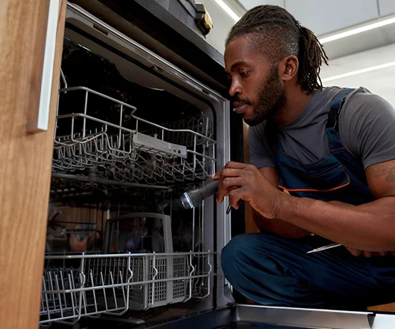 Technician working on a dishwasher, illustrating emergency dishwasher repair services in Jeffersonville IN.