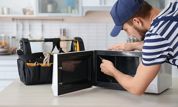Technician fixing a microwave, illustrating emergency home appliance repair availability.