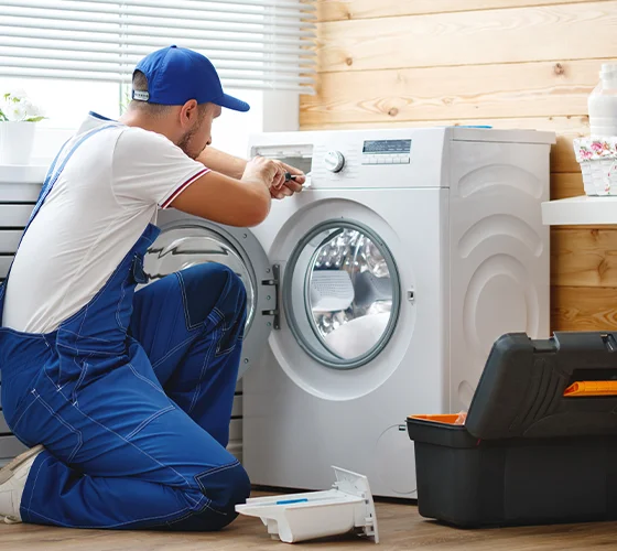 Technician repairing a washing machine, representing expert washer repair services in Louisville, KY.