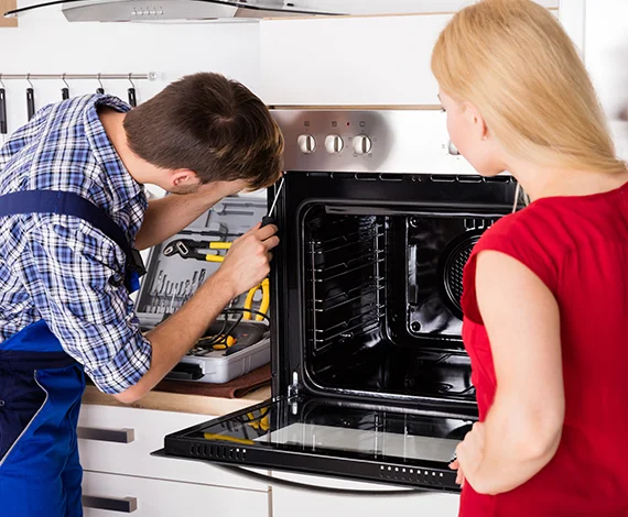 Technician repairing a home oven with a homeowner present, illustrating home oven repair services in Louisville, KY.