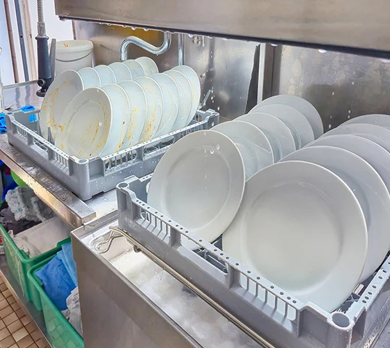 Clean dishes in a commercial dishwasher rack, representing hotel dishwasher repair services.