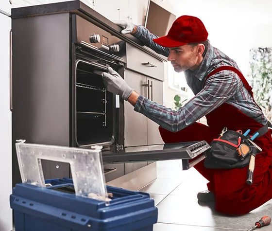 Technician repairing a commercial oven, representing restaurant oven repair services in Jeffersonville, IN.